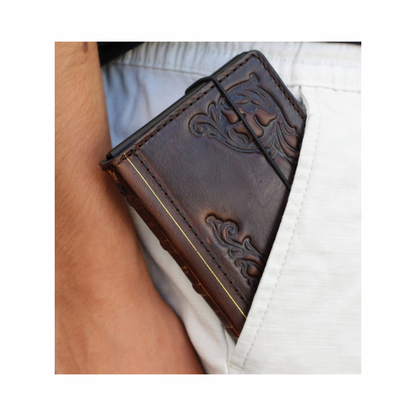 A close-up of a dark brown embossed leather wallet tucked into a white pocket on a person's hip.